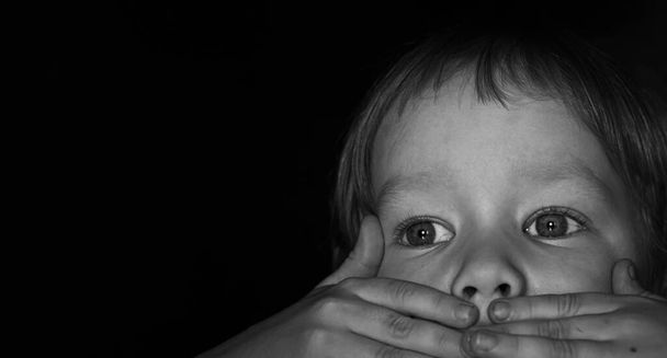 Portrait of a scared little boy child. The kid covered his mouth with his hands. The concept of stuttering, silence due to stress and shock. banner, copy space. - Photo, Image