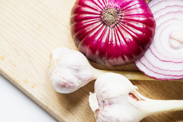 top view of red onion and garlic on wooden cutting board on white background - Fotografie, Obrázek