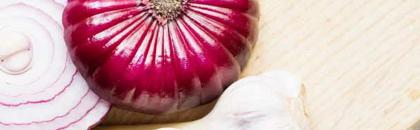 close up view of red onion and garlic on wooden cutting board, panoramic shot - 写真・画像