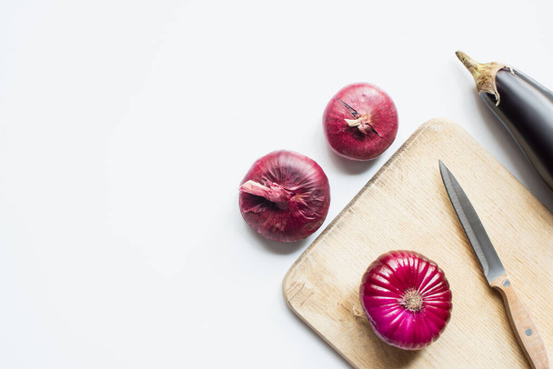 top view of purple whole vegetables, knife and wooden cutting board on white background - Zdjęcie, obraz