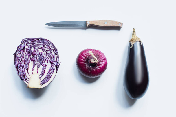 flache Lage mit Messer, rote Zwiebel, Rotkohl, Auberginen auf weißem Hintergrund - Foto, Bild