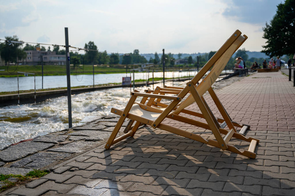Καρέκλες καταστρώματος στην άκρη ενός ποταμού λευκού νερού. - Φωτογραφία, εικόνα