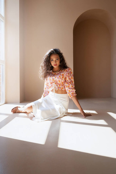 Mulatto female model posing on floor under sunlight. - Photo, Image