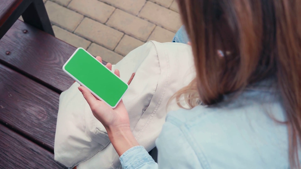 Selective focus of student holding smartphone with chroma key on bench  - Footage, Video