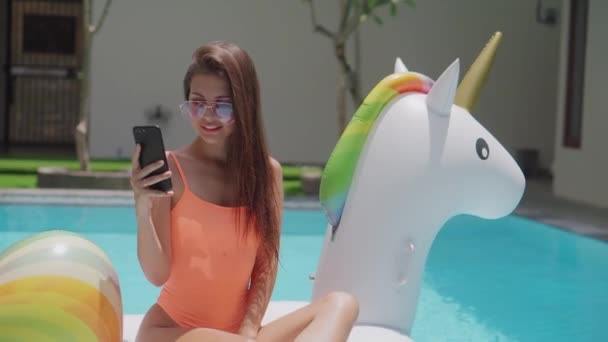 Милая молодая девушка выкладывает фотографии из бассейна в социальные сети в отпуске - Кадры, видео
