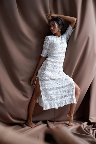 Mulatto female model posing among fabric. - Фото, изображение