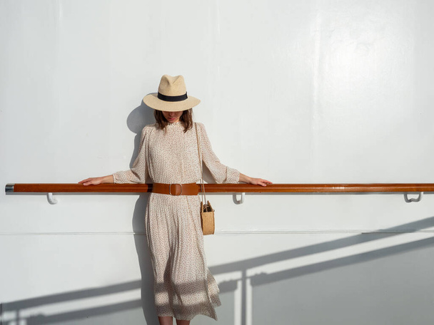 Mujer joven en un sombrero junto a la pared en el sol
 - Foto, Imagen