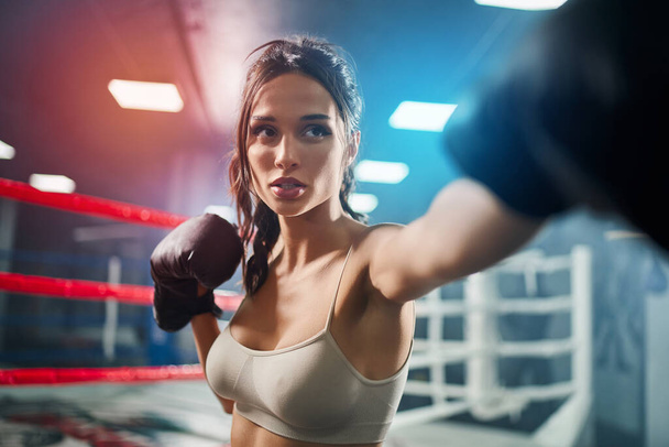 Woman showing hit in boxing gloves. - 写真・画像