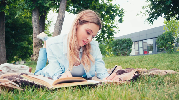 Студент читає книгу і пише на блокноті в парку
  - Кадри, відео
