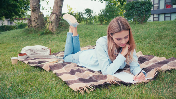 Student psaní na notebooku u knih a kávy jít na kostkované v parku  - Záběry, video