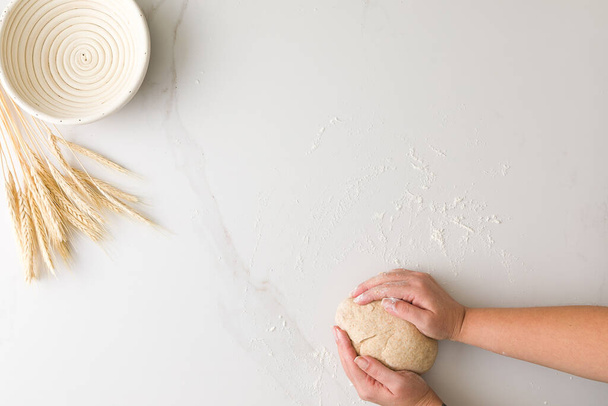 Vue du dessus de la pâte à pain moulée à la main féminine dans une table en marbre avec un bol à pain vide et du blé avec espace pour le texte - Photo, image