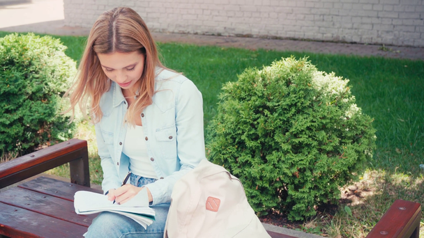 Studenten schrijven op notebook terwijl ze op een bankje in de stad zitten  - Video