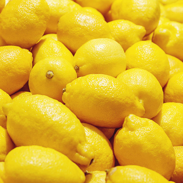 yellow lemons close up at fruit market, bright lemon background - Фото, зображення