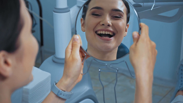 Dentista che dà specchio al paziente allegro in clinica  - Filmati, video