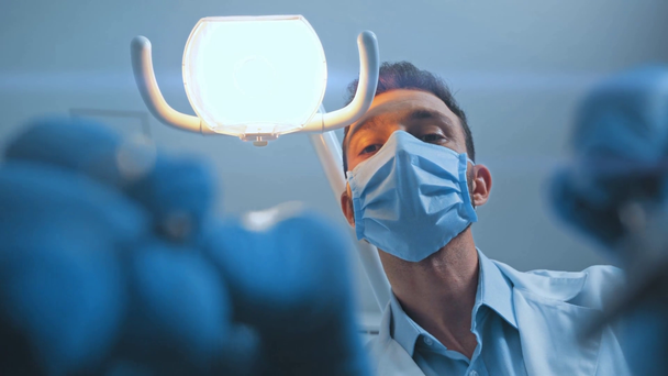 Visão de baixo ângulo do dentista usando instrumentos dentários e mostrando como na câmera
  - Filmagem, Vídeo