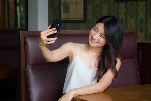 Portrait of thai china adult beautiful girl White shirt blue jeans using her smart phone Selfie - Photo, image