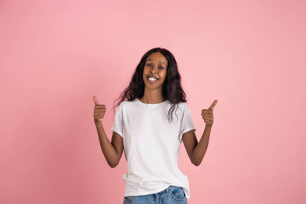 Cheerful african-american young woman isolated on pink background, emotional and expressive - Фото, изображение