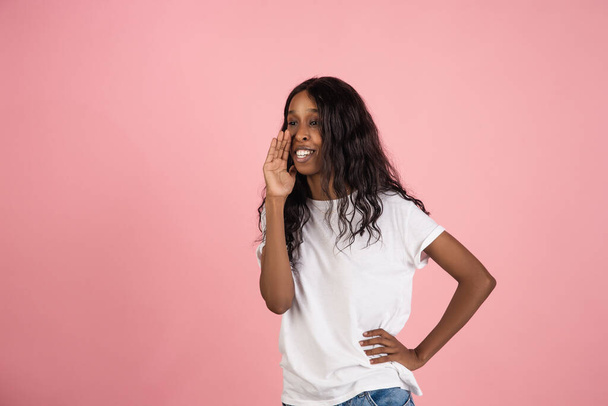 Cheerful african-american young woman isolated on pink background, emotional and expressive - Valokuva, kuva