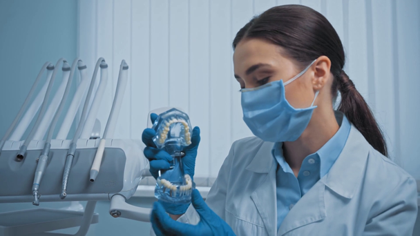 Dentista en punto máscara médica con el dedo en el modelo de dientes en la clínica
 - Imágenes, Vídeo