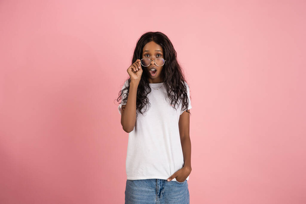 Cheerful african-american young woman isolated on pink background, emotional and expressive - Фото, изображение