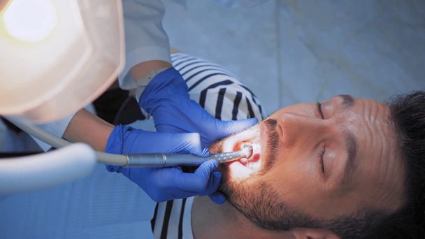 Οδοντίατρος που χρησιμοποιεί οδοντιατρικό όργανο ενώ εργάζεται με ασθενή στην κλινική  - Πλάνα, βίντεο