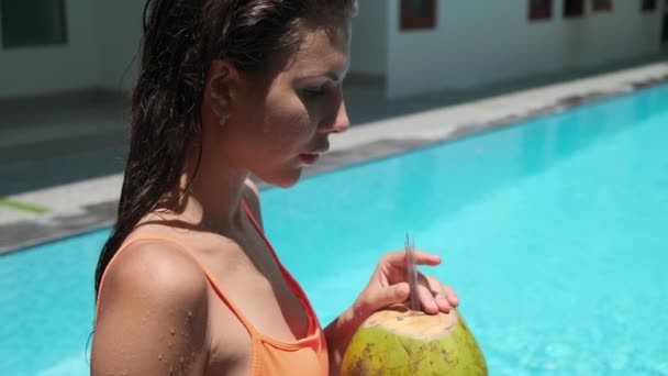 žena pije kokosový koktejl v bazénu - Záběry, video
