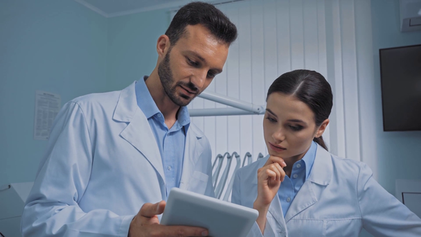 Dentistas hablando y usando tableta digital en la clínica
  - Metraje, vídeo