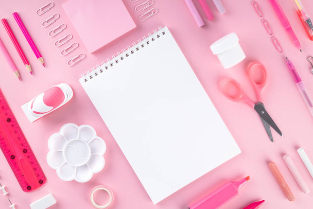 Various school office and painting supplies on pink background. Back to school concept. Geometric and monochrome composition. Top view. Copy space - 写真・画像