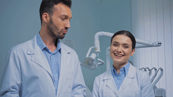 Οδοντίατροι χαμογελούν κοιτάζοντας κάμερα στην κλινική  - Πλάνα, βίντεο