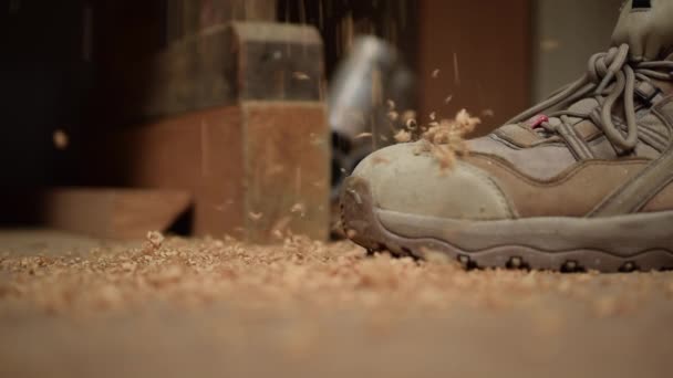 Trociny opadające na ziemię obok butów roboczych w zwolnionym tempie - Materiał filmowy, wideo