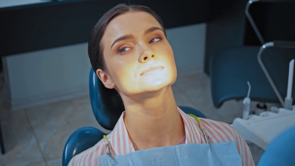 Dentist examining teeth of attractive patient in clinic  - Imágenes, Vídeo