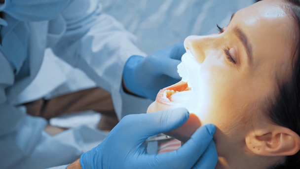 Zubař v latexových rukavicích vyšetřuje zuby pacienta na klinice  - Záběry, video