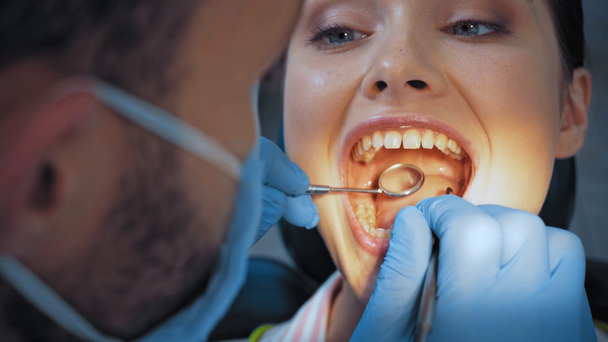 Foco seletivo do médico com espelho dentário examinando os dentes do paciente na clínica
  - Filmagem, Vídeo
