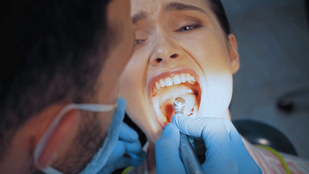 Medico che utilizza lo strumento dentale mentre il paziente sente dolore in clinica  - Filmati, video