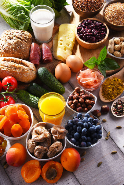 Composición con una variedad de productos alimenticios orgánicos en la mesa de cocina de madera. - Foto, Imagen