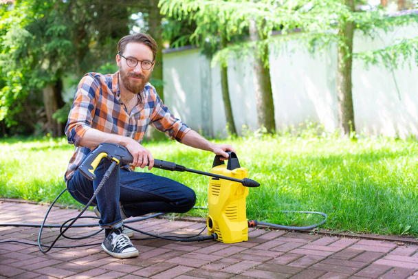 Man using a high pressure washer in the backyard, on a sunny day. - Foto, Imagem