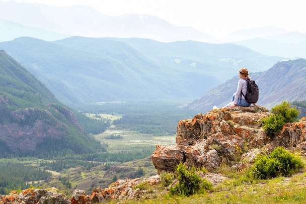  リュックに座って山の景色を見て女性旅行者。旅行、アクティブなライフスタイルと夏休みのコンセプト. - 写真・画像