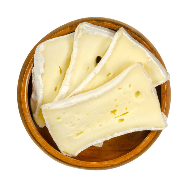 Кусочки мягкого сыра в деревянной миске. Влажный сливочный сыр, изготовленный из коровьего молока, созрел на поверхности специальным грибком. Известный как Камамбер или Бри. Крупный план, сверху, фото макропродовольствия. - Фото, изображение