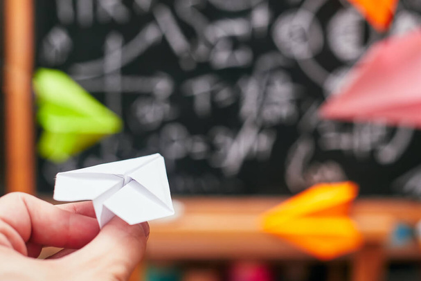 concepto de la escuela, la mano lanza un pequeño avión de papel en una junta escolar, universidad
 - Foto, imagen