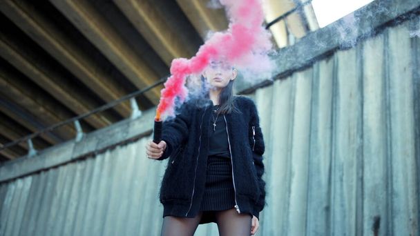 Mujer joven posando en la cámara con colorida bomba de humo. Chica protestando al aire libre
 - Foto, Imagen