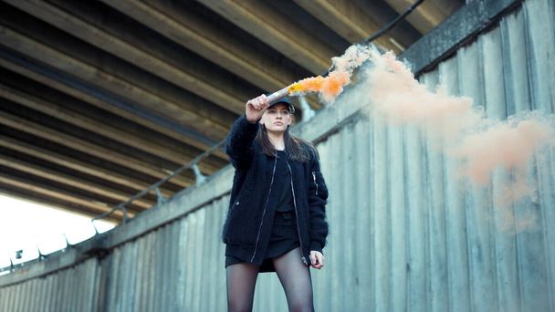 Κορίτσι που κρατάει καπνογόνο στο δρόμο. Ακτιβιστική διαμαρτυρία με πολύχρωμη χειροβομβίδα καπνού - Φωτογραφία, εικόνα