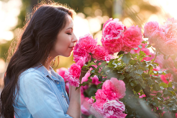 Женщина 25-26 лет, держащая в руках розовые розовые цветы в саду. Летний сезон. 20-е годы.  - Фото, изображение