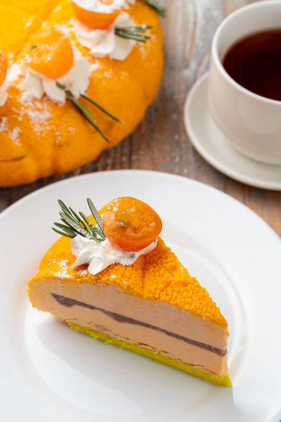 A slice orange souffle cake with tea and a whole torte on background - Foto, imagen