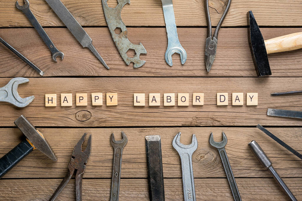 Happy Labor Day Konzept Baugruppe Heimwerkzeuge - Hammer, Säge, Schraubendreher, Meter, Zange, Schraubenschlüssel, Meißel auf hölzernem Hintergrund. - Foto, Bild