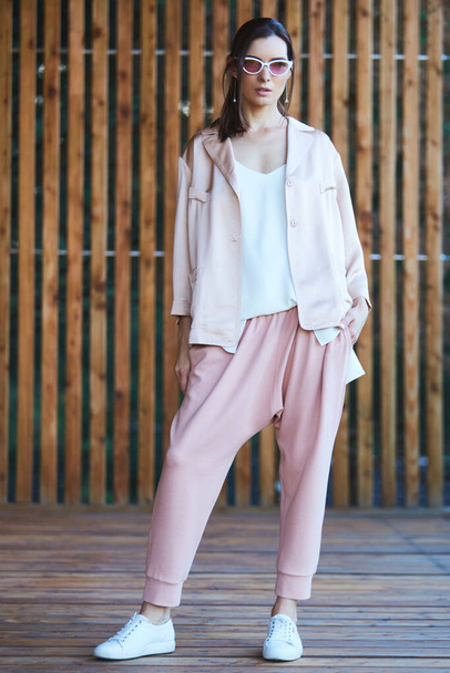 Woman in pink pants on wooden terrace. - Фото, изображение