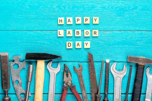 Happy Labor Day concept Stavební skupina domácí nářadí - kladivo, pila, šroubovák, metr, kleště, klíč, dláto na modrém dřevěném pozadí Rekreační karta Top view Flat lay Text Banner. - Fotografie, Obrázek