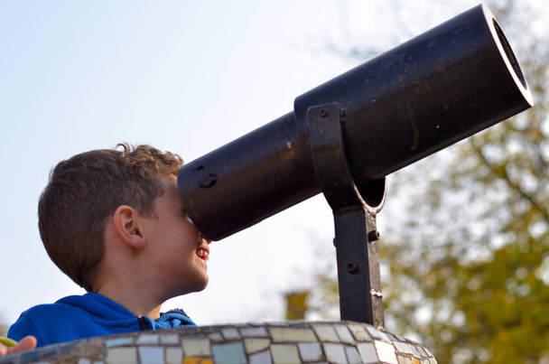 Il bambino guarda attraverso il binocolo su un parco giochi - Foto, immagini