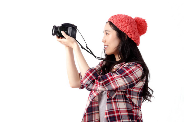Egy ázsiai nő kockás inget visel, kamerával rögzíti az utazásokat, fehér háttér. - Fotó, kép