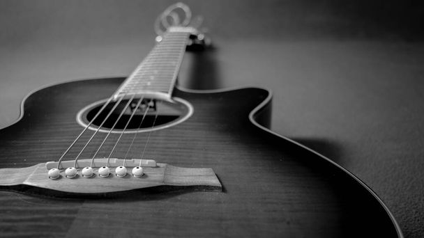 Retrato de uma bela guitarra eletroacústica deitada no lado esquerdo, mostrando a ponte, a boca, o pescoço e suas cordas
 - Foto, Imagem