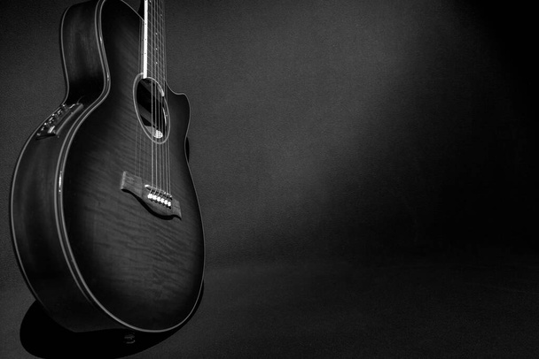 Belle guitare électro acoustique debout sur le côté, vous pouvez voir le boîtier et une partie du cou, sur un fond sombre, n'éclairant que la guitare. - Photo, image